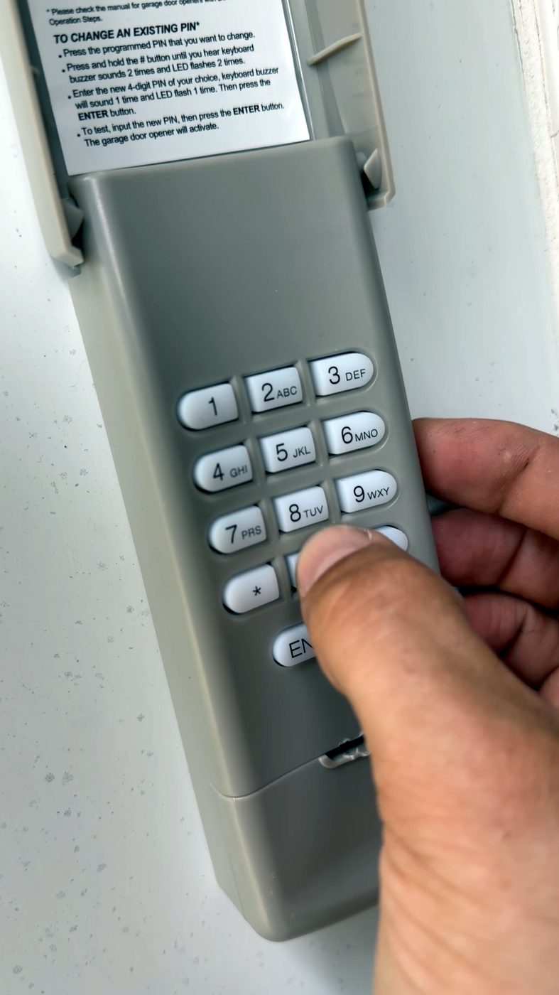 A standard wireless garage keypad being programmed — code entry only, no camera